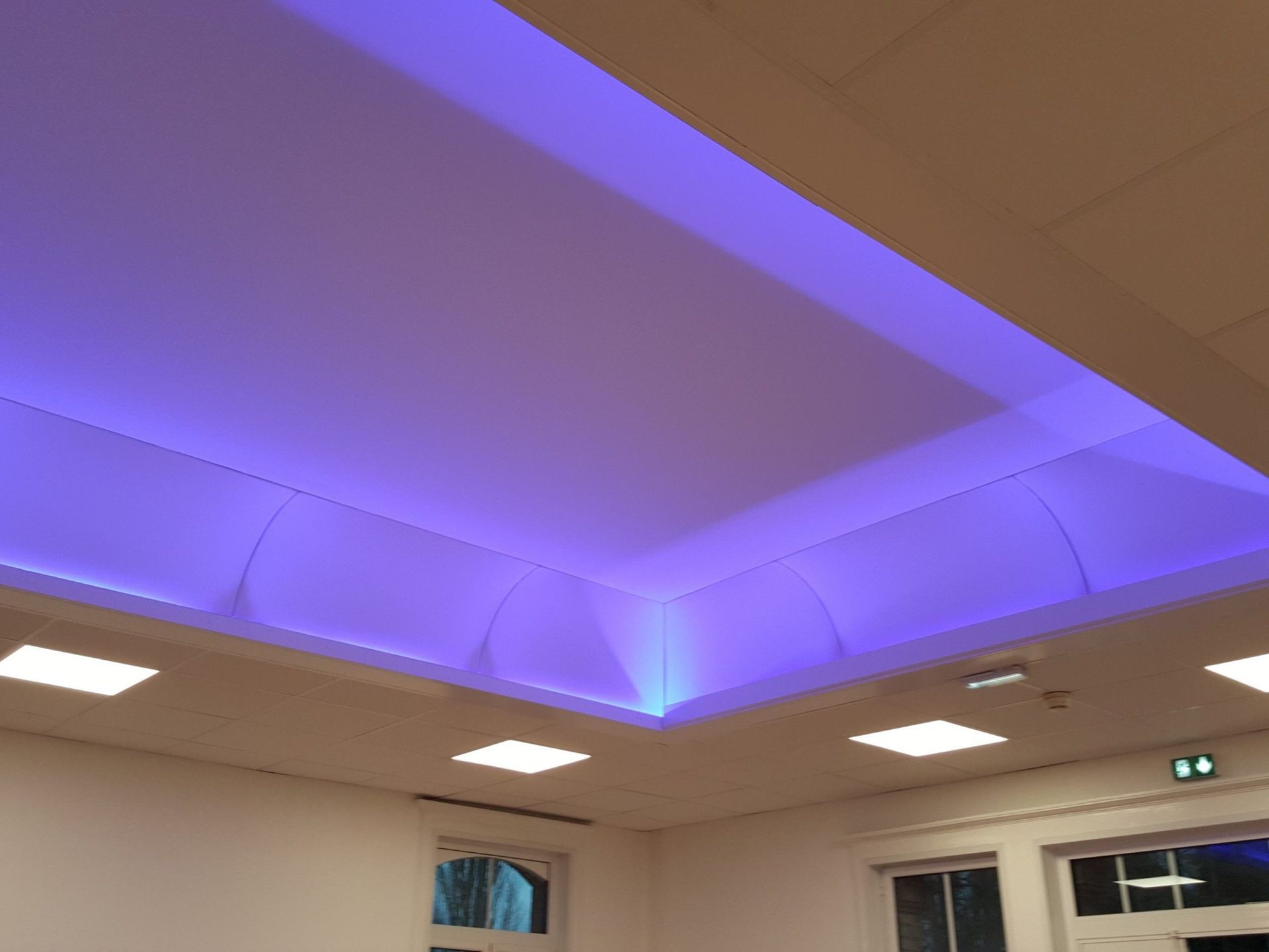 Plafond avec zone encastrée éclairée en bleu, comportant des spots encastrés carrés.