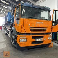 Un camión naranja está estacionado en un garaje con las puertas abiertas.