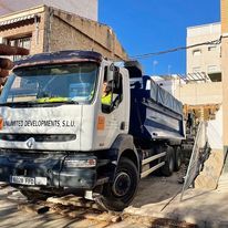 Un camión volquete está estacionado frente a un edificio.