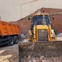 Una excavadora está cargando tierra en un camión volquete naranja.