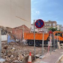 Un camión volquete está estacionado frente a un edificio en construcción.