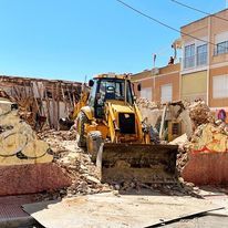 Una excavadora está demoliendo un edificio en una ciudad.