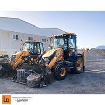 Dos excavadoras están estacionadas una al lado de la otra frente a un edificio.