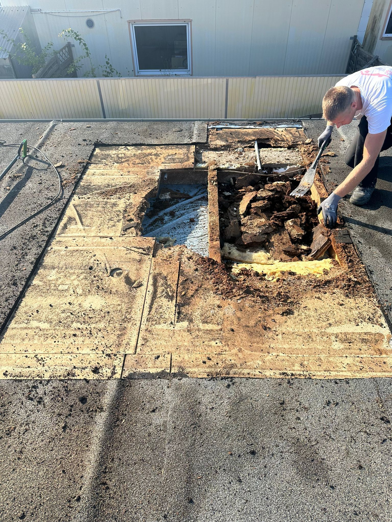 Ein Mann arbeitet mit einer Schaufel auf einem Dach.