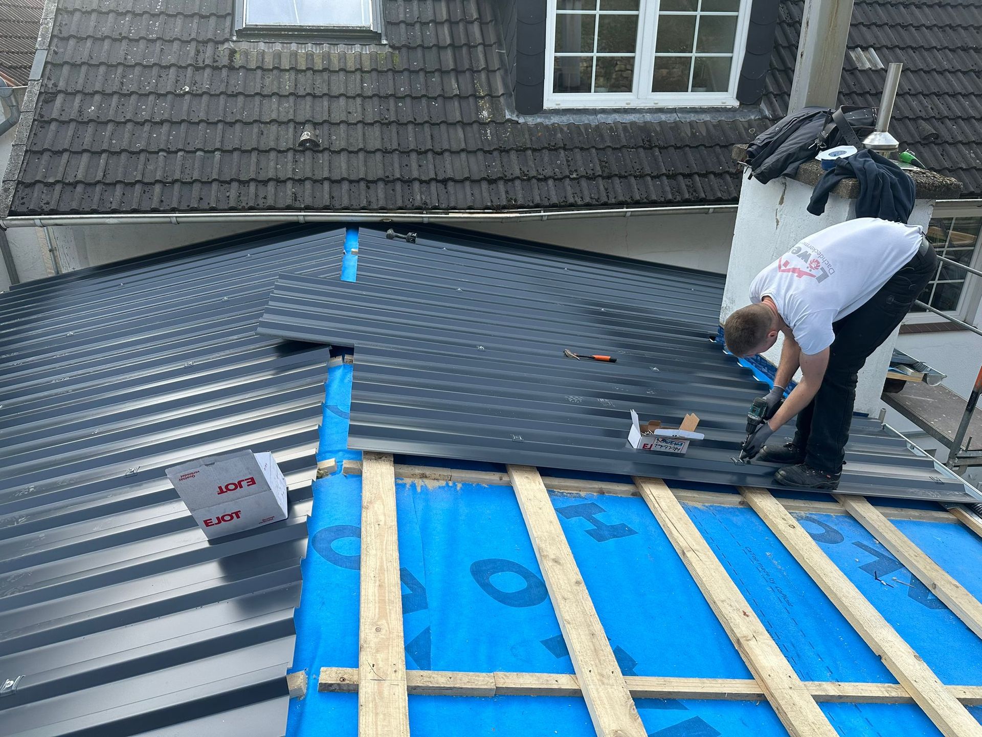 Ein Mann arbeitet auf dem Dach eines Hauses.
