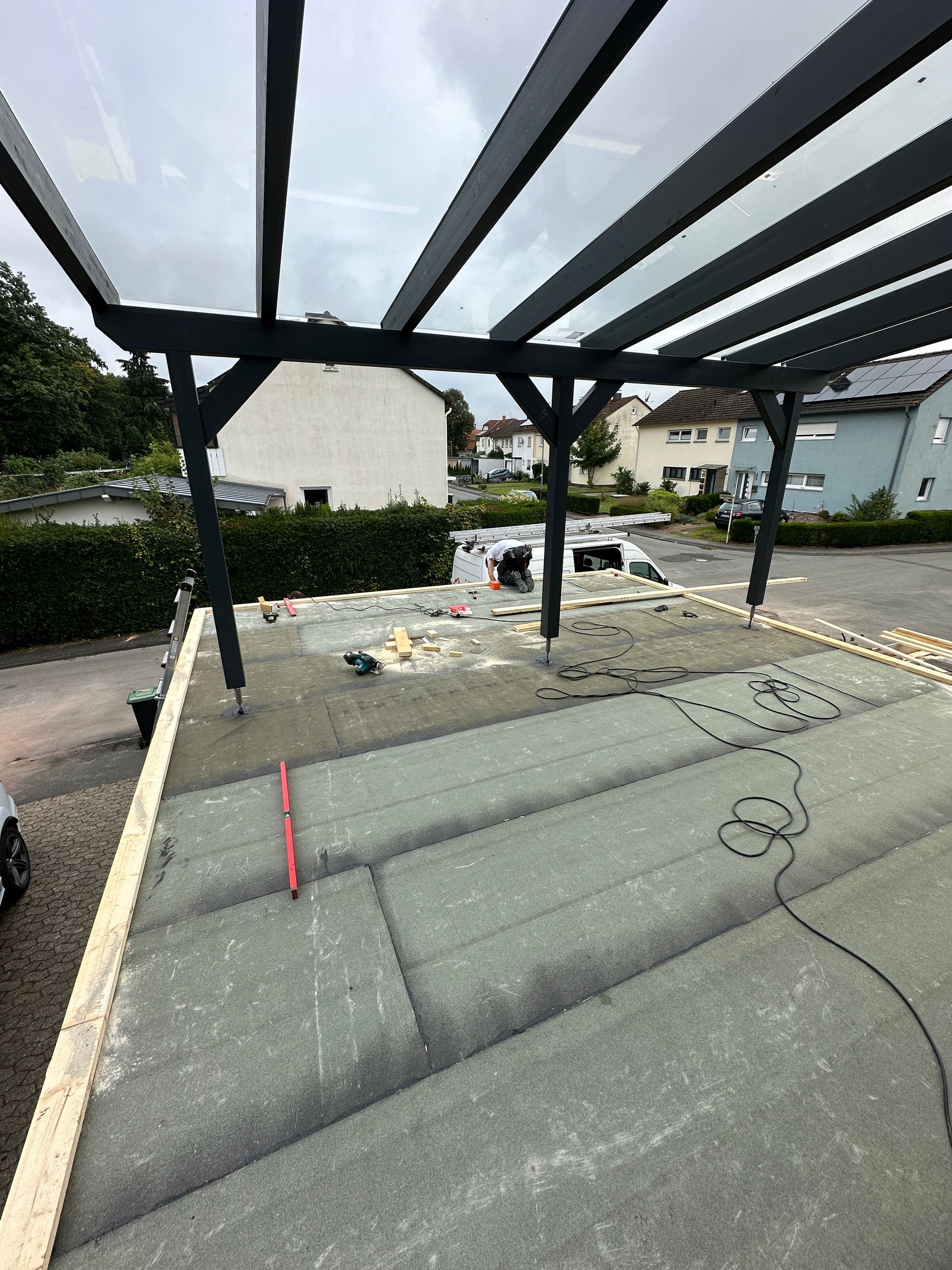 In einer Einfahrt neben einem Haus wird ein Carport gebaut.