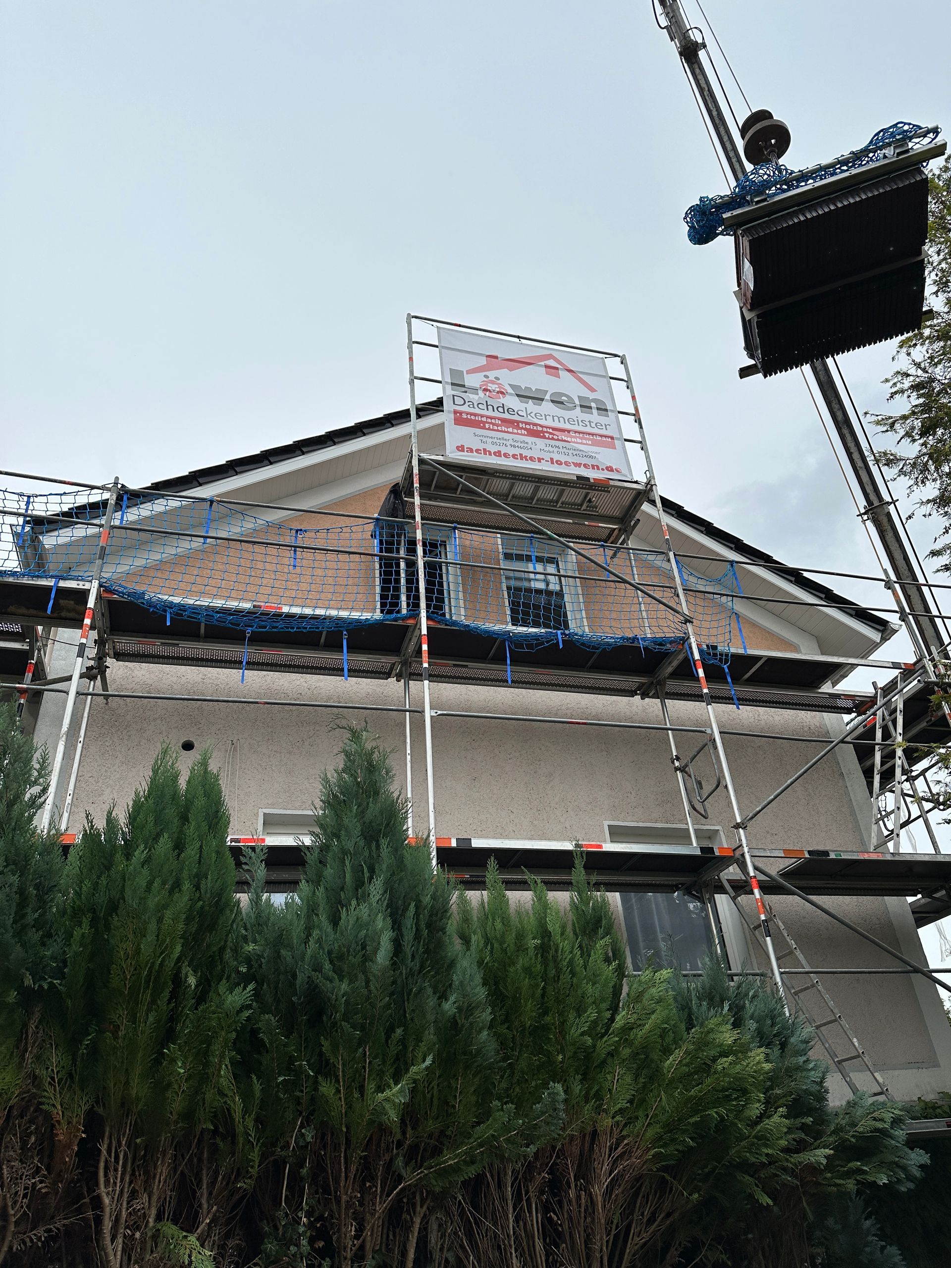 Ein Kran hebt eine Kiste auf ein Gebäude.