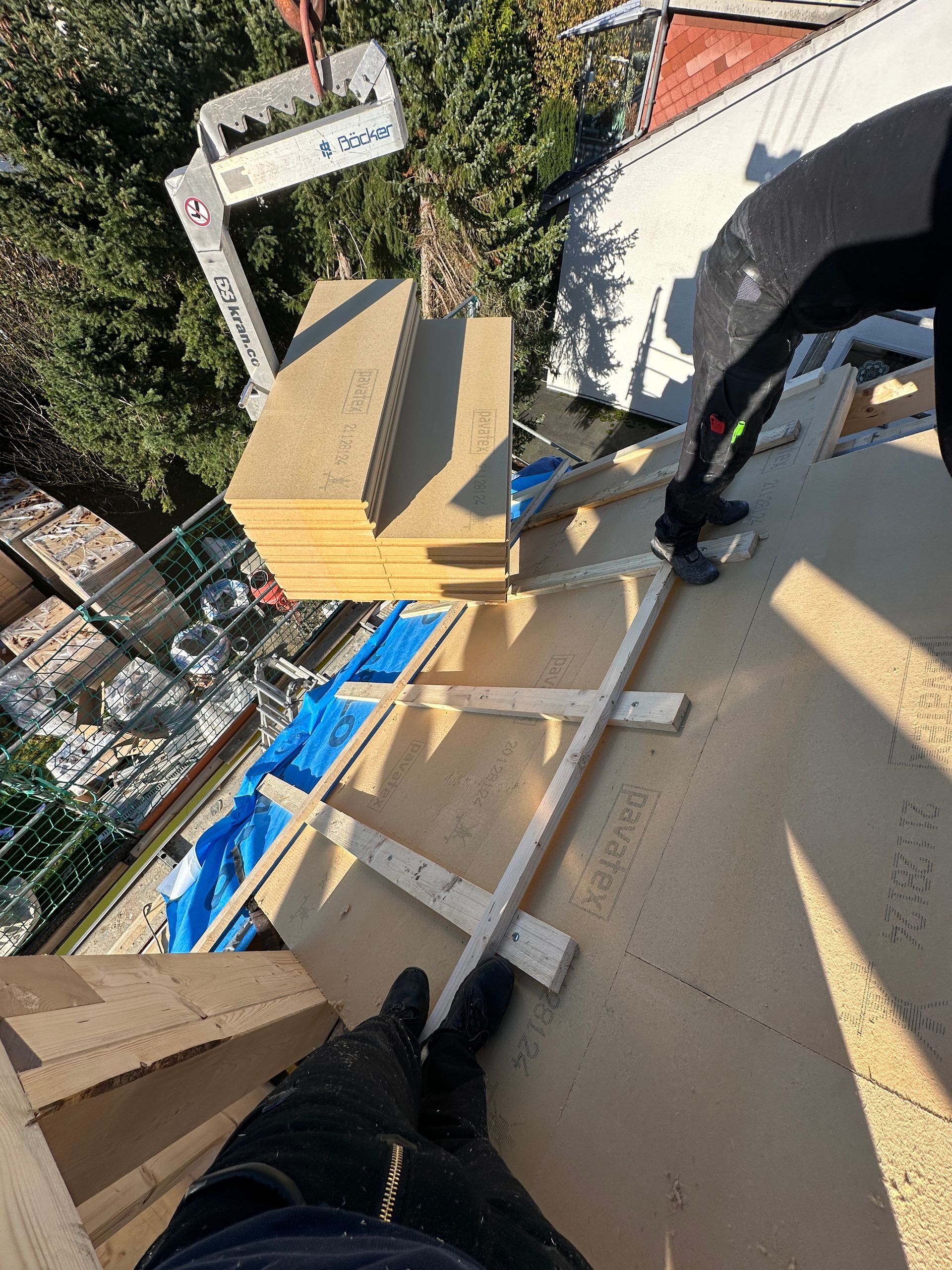 Eine Person steht auf einer Leiter auf einem Holzdach.