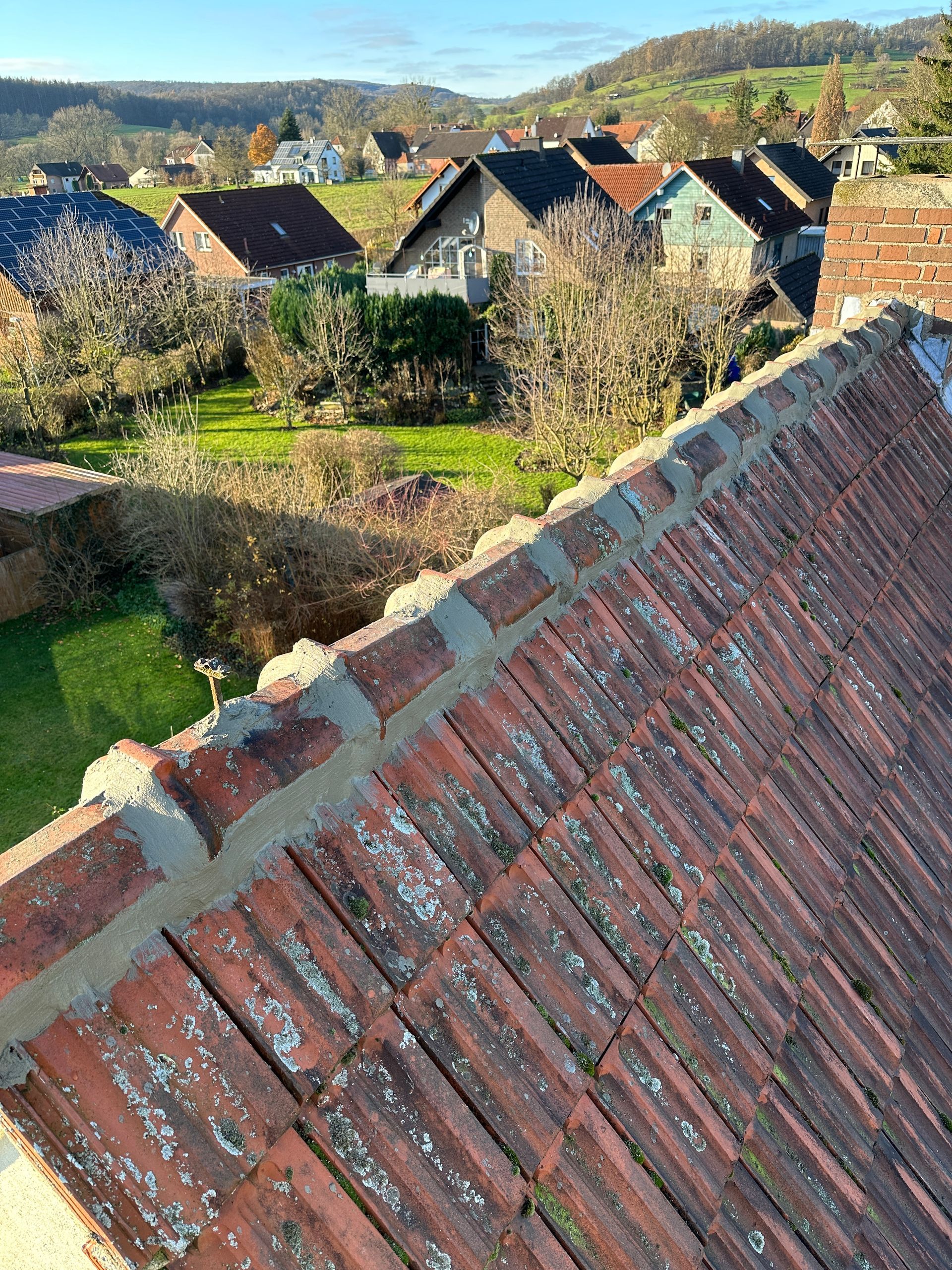 Ein Dach mit vielen Ziegeln darauf und eine Häuserreihe im Hintergrund.