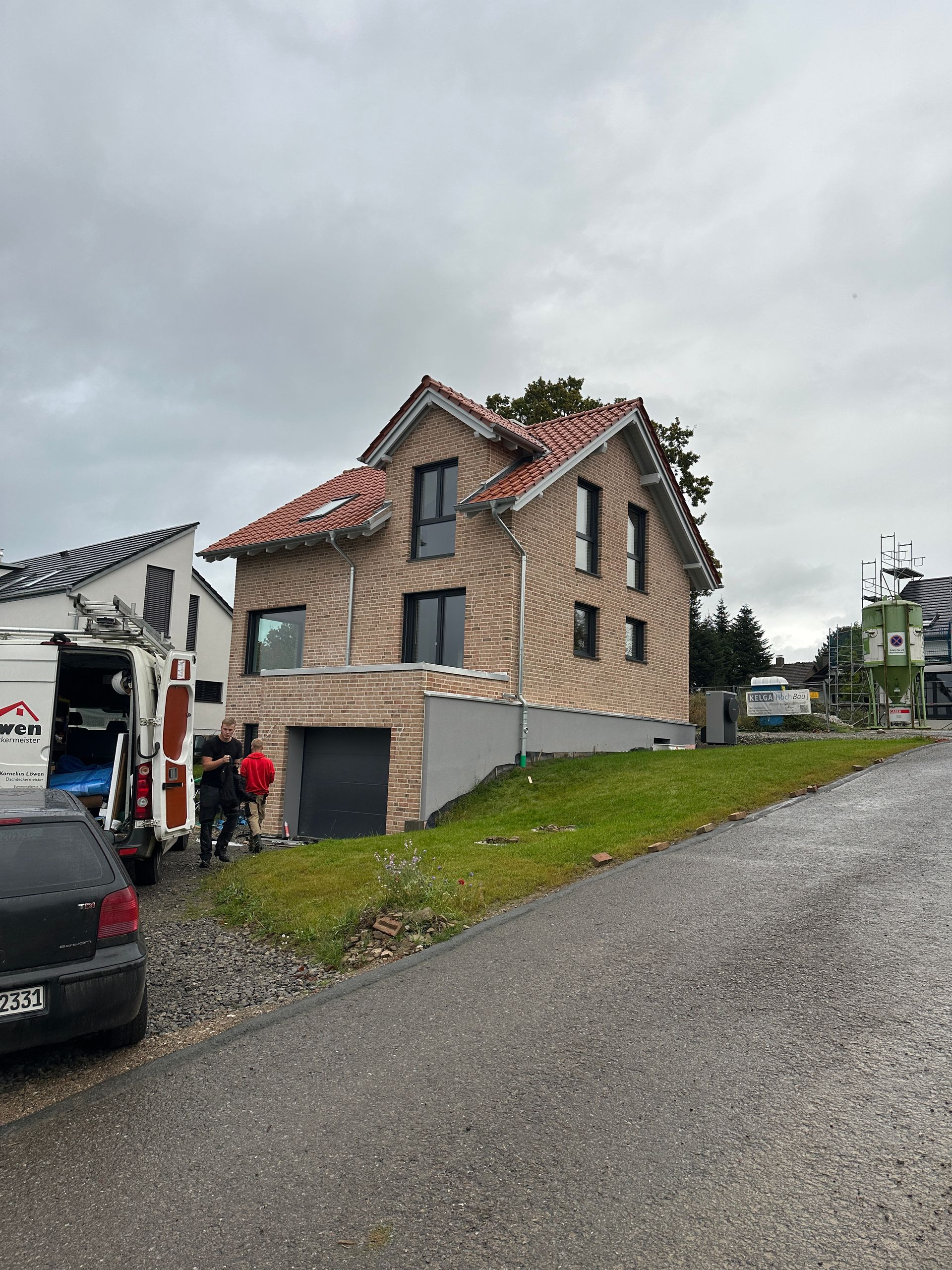Vor einem im Bau befindlichen Haus ist ein Auto geparkt.