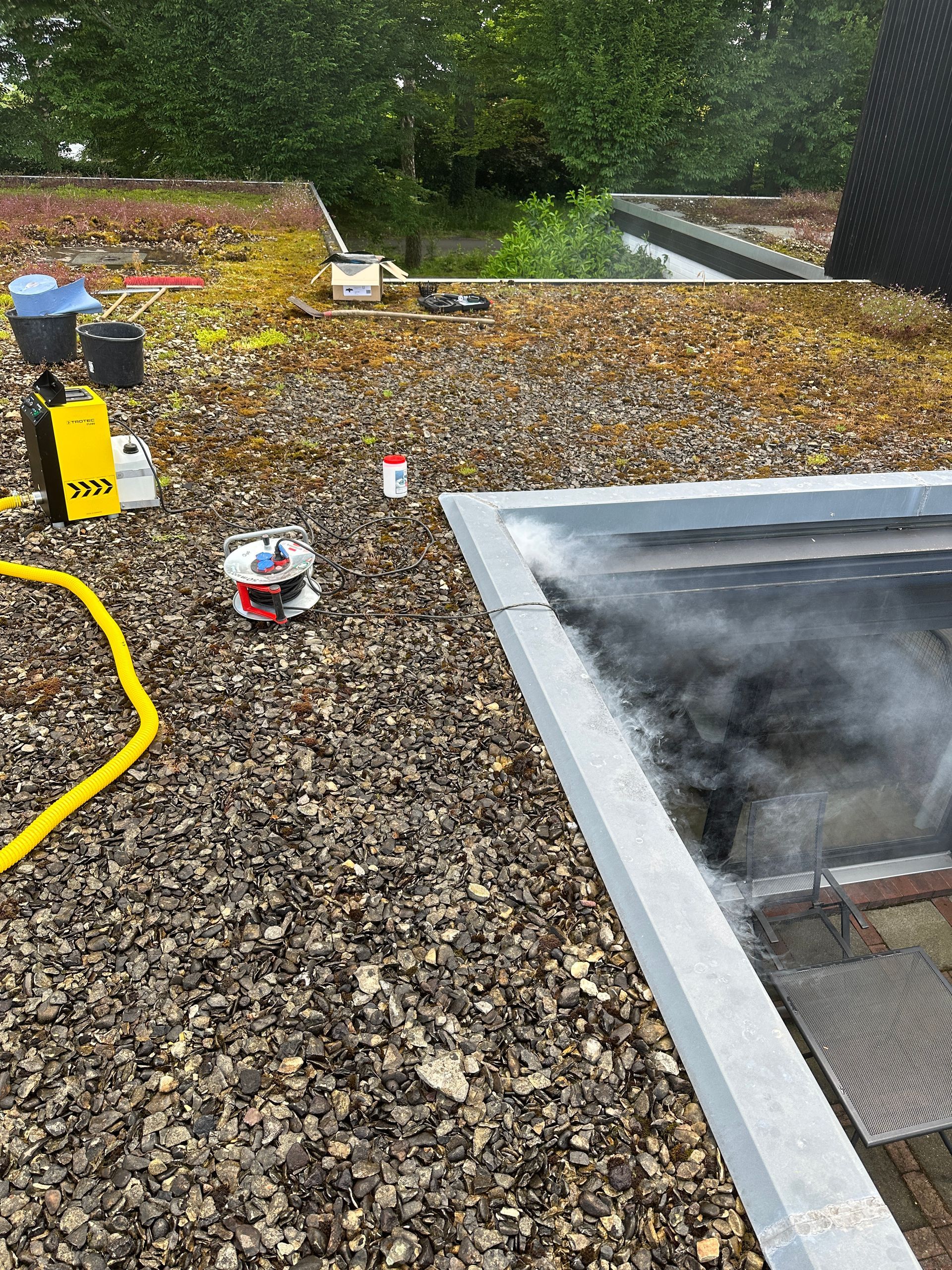 Ein Schlauch liegt auf einem Kiesdach neben einem Pool.