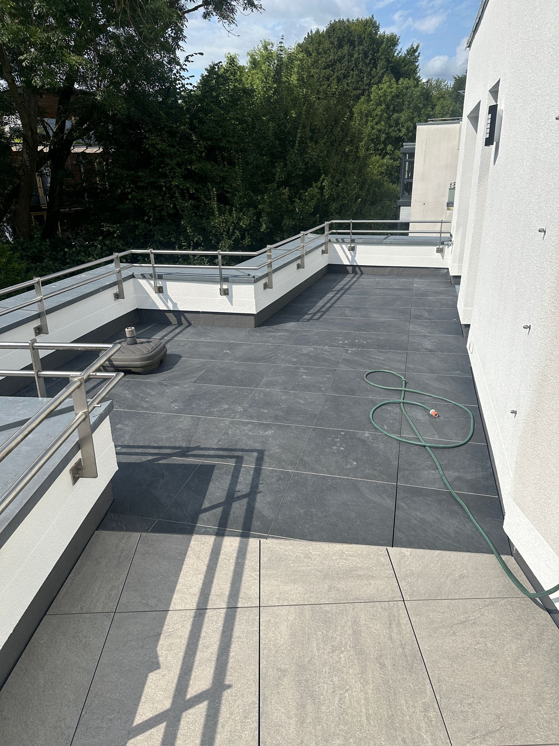 Eine Dachterrasse mit Geländer und Bäumen im Hintergrund