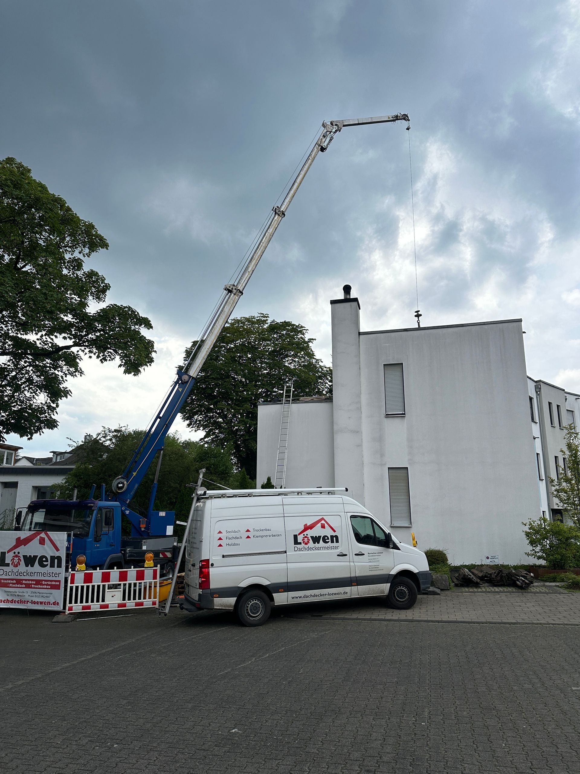 Ein weißer Lieferwagen steht vor einem Gebäude mit einem Kran auf dem Dach.