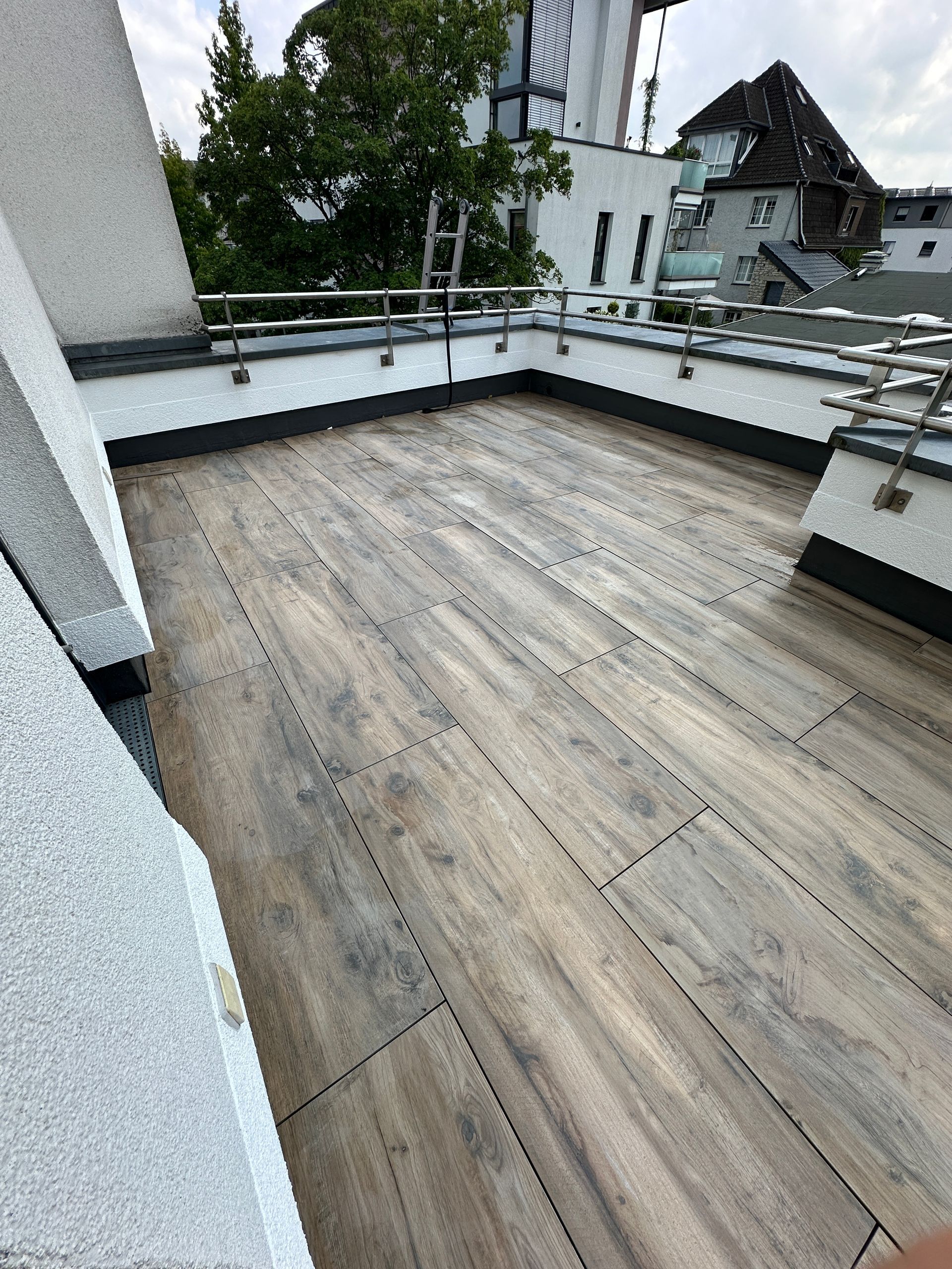 Eine Dachterrasse mit Holzboden und Geländer.
