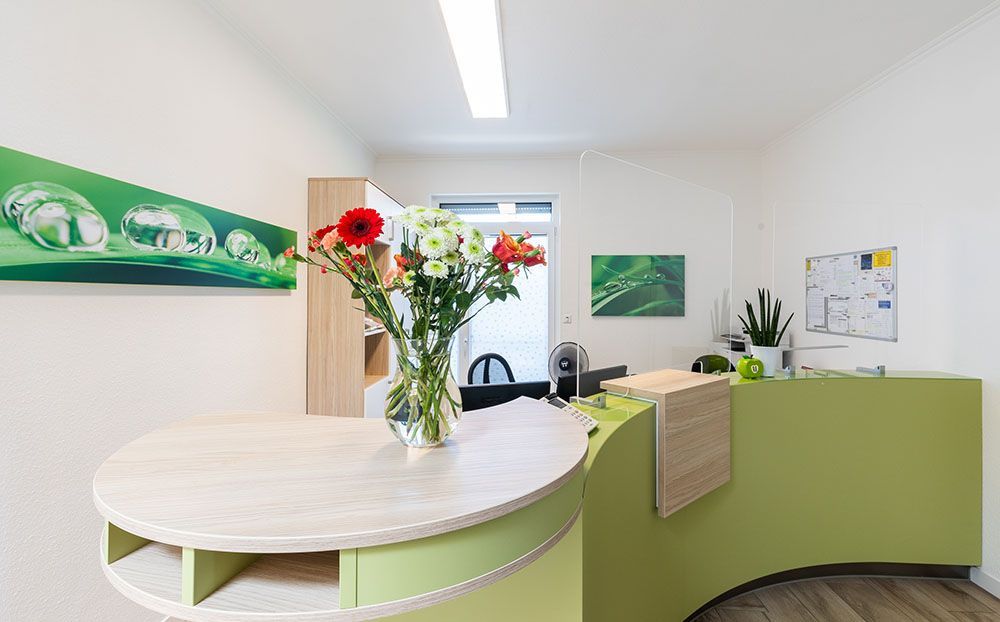 Ein grüner Rezeptionstresen mit einer Vase mit Blumen darauf.