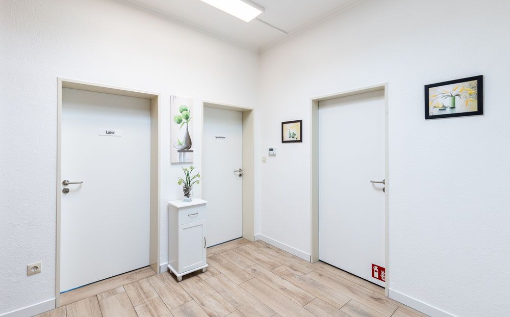 Ein Flur mit weißen Türen und Holzboden.