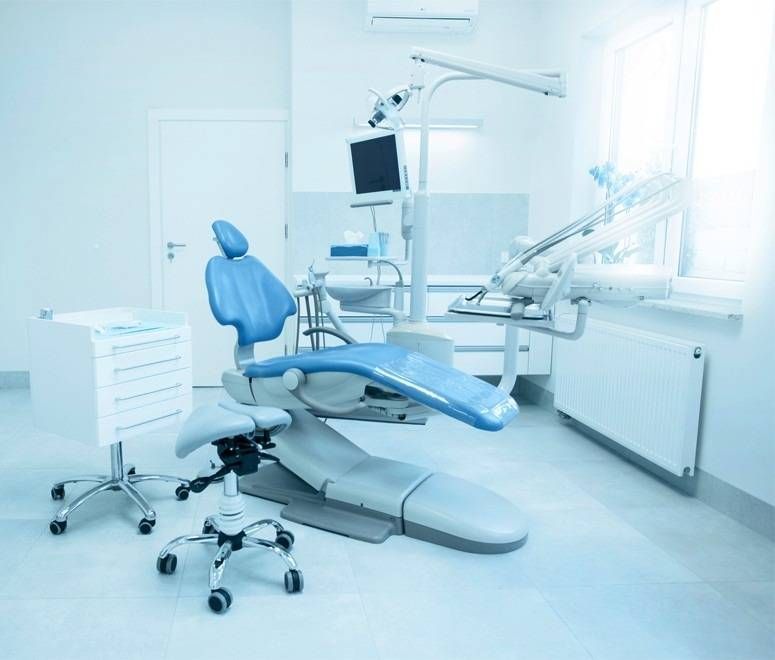 Zahnarztzimmer mit blau-silbernem Zahnarztstuhl und -geräten.