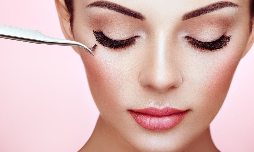 Una mujer se está depilando las pestañas con pinzas.
