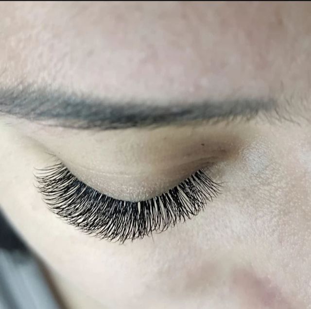 Primer plano de un ojo cerrado con pestañas negras largas y tupidas y una ceja natural.