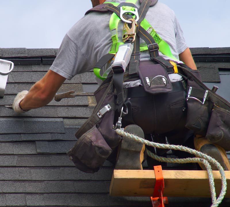 Employé sur un toit harnaché pour sa sécurité