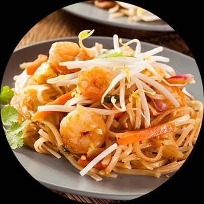 Pad Thai con camarones, zanahorias, brotes de soja y hierbas en un plato gris.