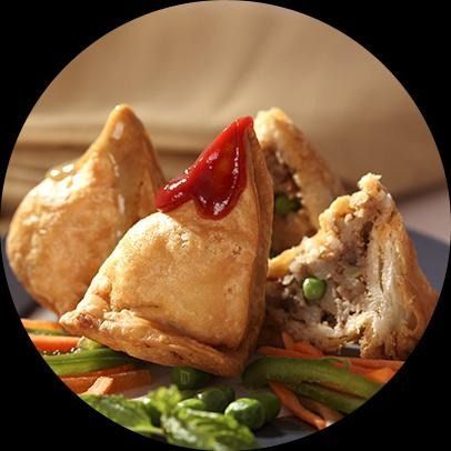 Samosas con salsa para mojar y verduras en un plato.