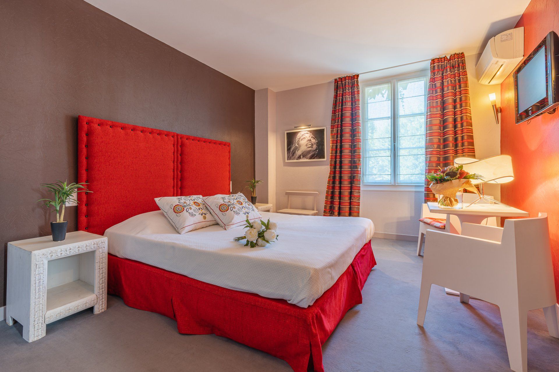 Chambre cosy avec tête de lit rouge et bureau près de la fenêtre