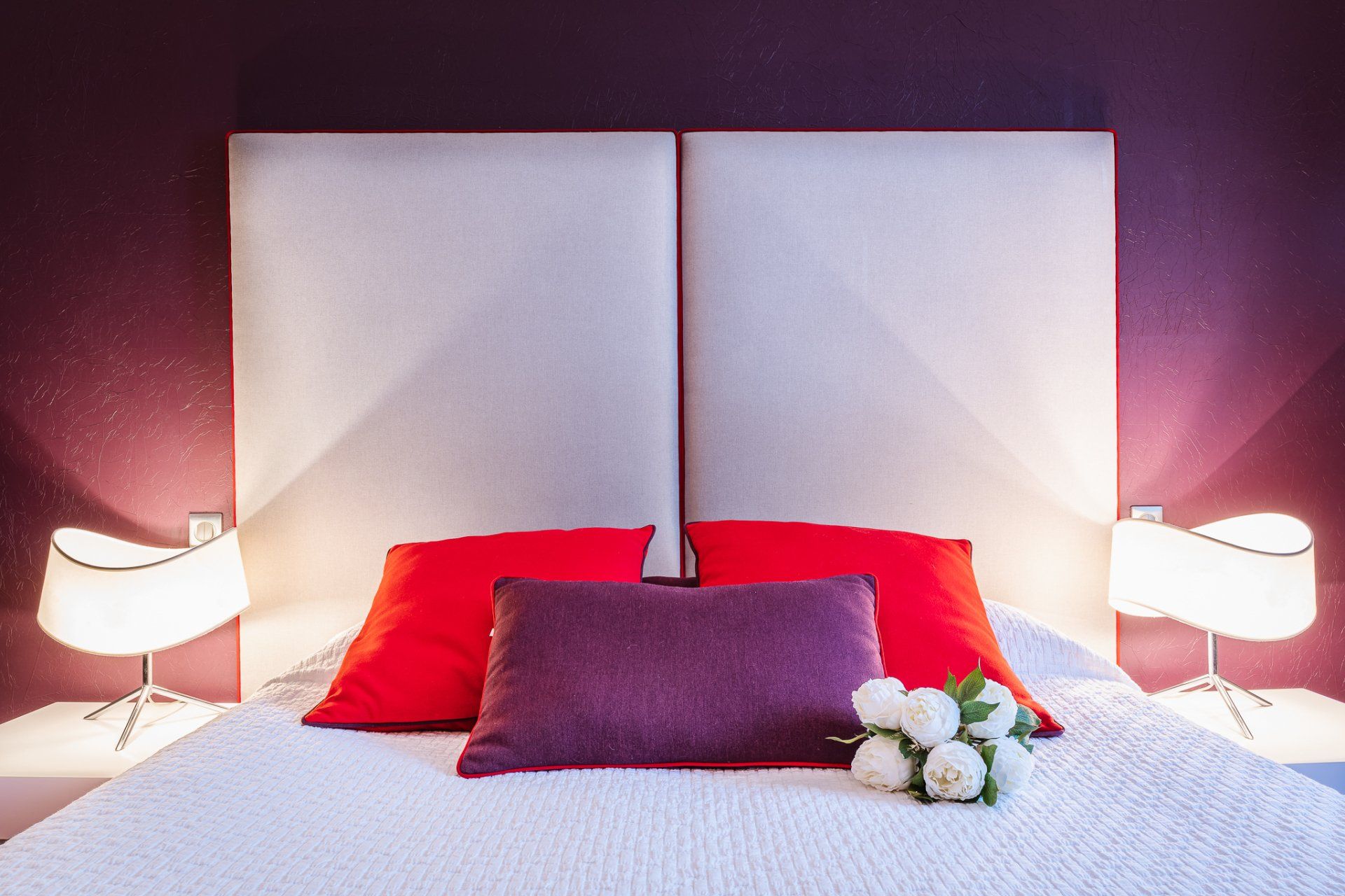 Chambre lumineuse avec tête de blanche et coussins rouges et violets