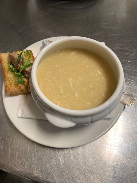 Un bol blanc rempli de soupe crémeuse, accompagné de deux morceaux de pain grillé garnis d'herbes