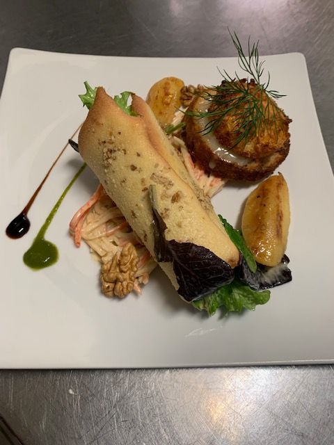 Plat élégamment dressé comprenant de la viande roulée, des légumes rôtis et des sauces disposées autour des aliments