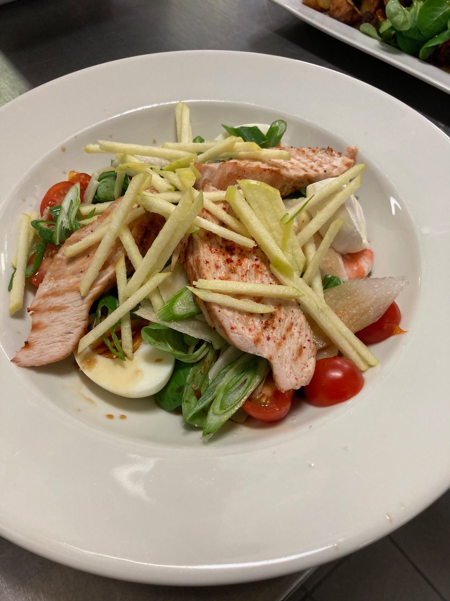 Assiette de salade avec des tranches de poulet grillé, des tomates cerises, des tranches d'œufs durs et de la vinaigrette