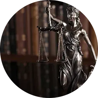 Una estatua de la Dama de la Justicia sosteniendo una balanza de la justicia frente a una estantería.