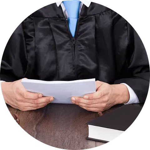 Un hombre con toga y birrete de graduación sostiene un trozo de papel en sus manos.