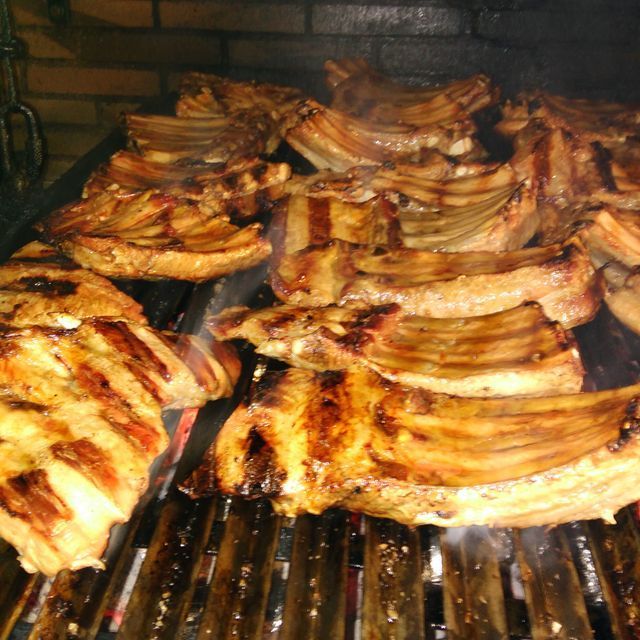 Un montón de carne se está cocinando en una parrilla