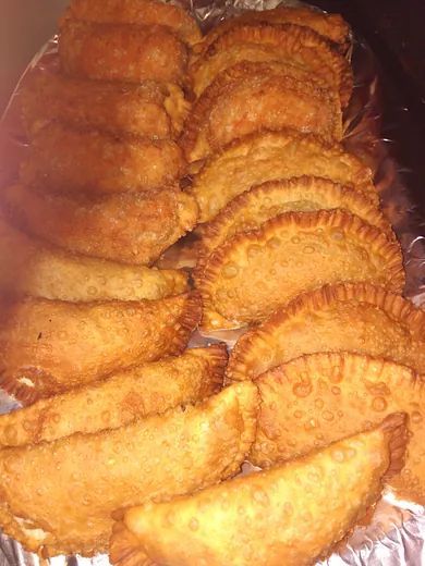 Una bandeja de pasteles fritos sobre papel de aluminio sobre una mesa.
