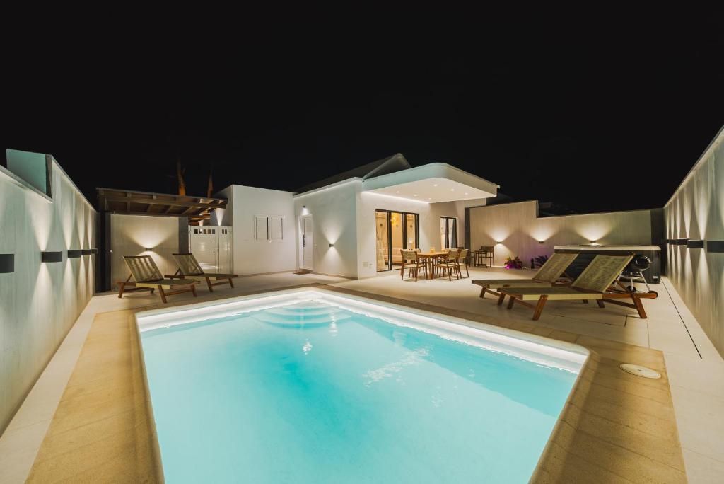 Piscina privada de Villa Moon iluminada de noche, con tumbonas y comedor exterior