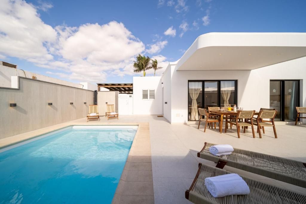 Piscina privada de día con tumbonas y zona de comedor exterior