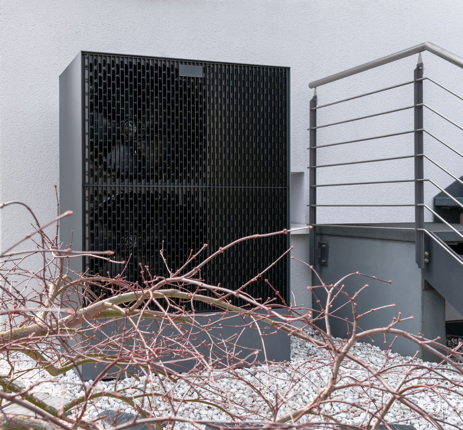 Pompe à chaleur air-eau installée à proximité d’un escalier extérieur sur un bâtiment rénové sur le plan énergétique.