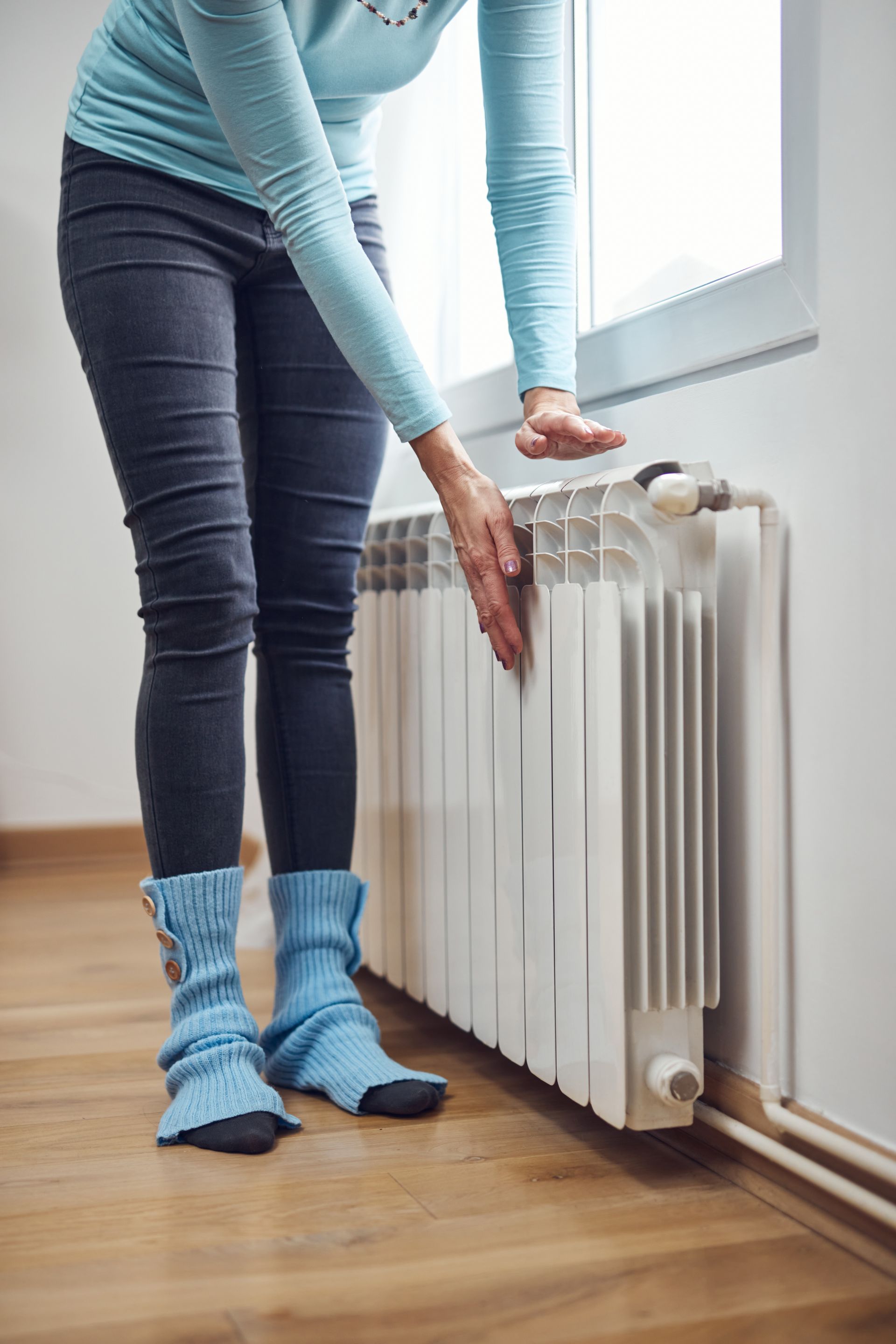 Une personne se réchauffe les mains près d’un radiateur en hiver.