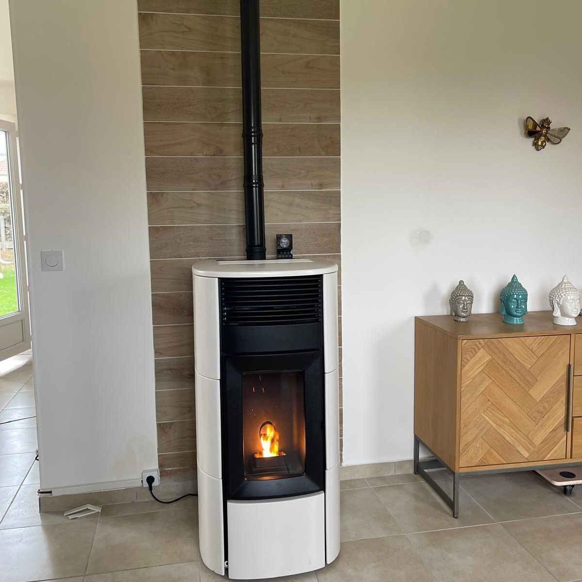 Poêle à granulés blanc moderne avec une petite flamme dans un salon à côté d'un meuble en bois