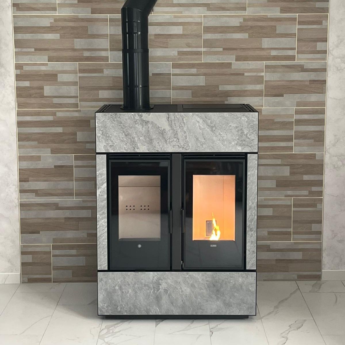 Cuisinière à bois moderne avec habillage effet pierre installée dans un intérieur.