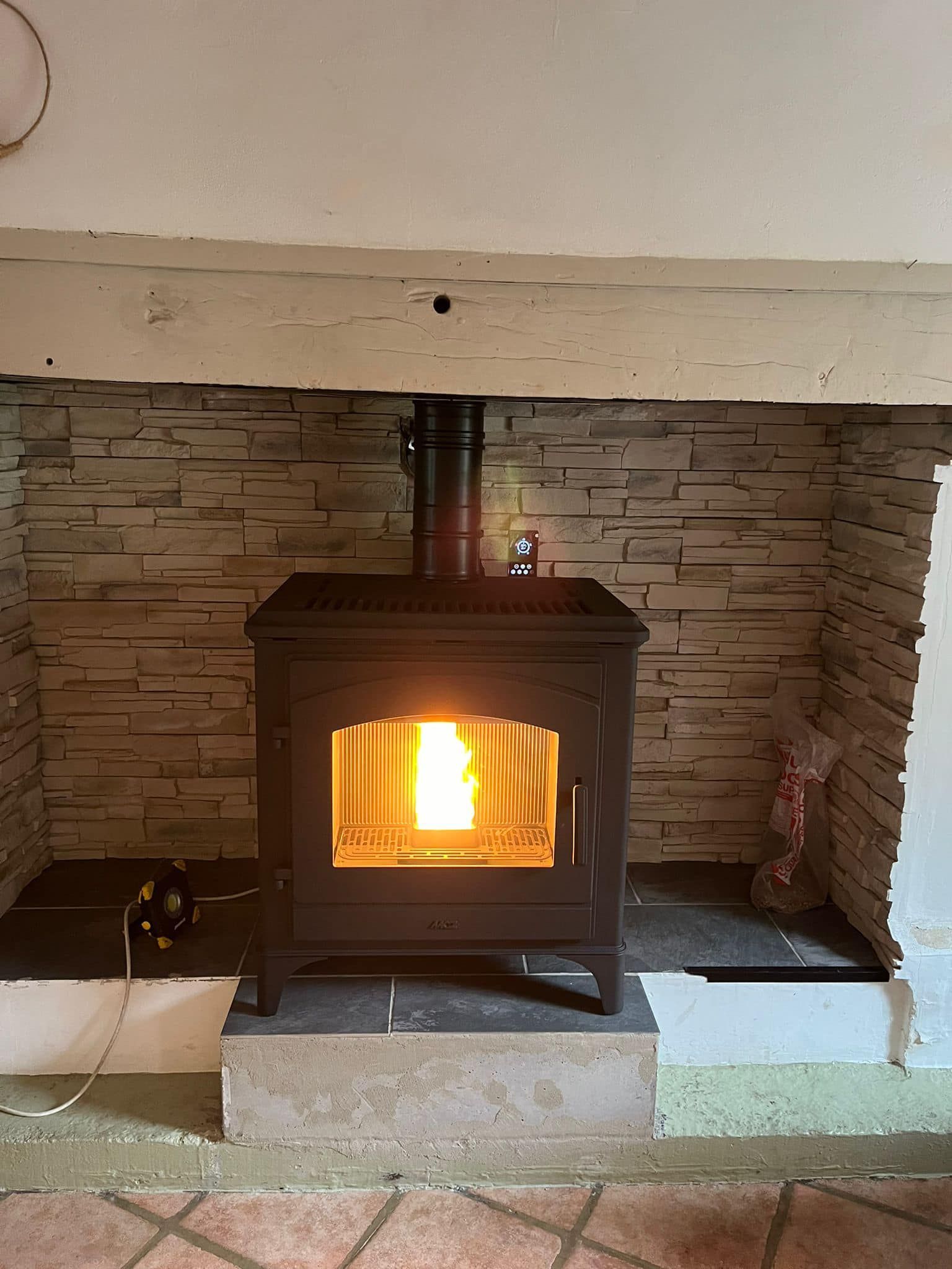 Poêle à bois allumé dans une cheminée en briques avec un feu vif à l'intérieur