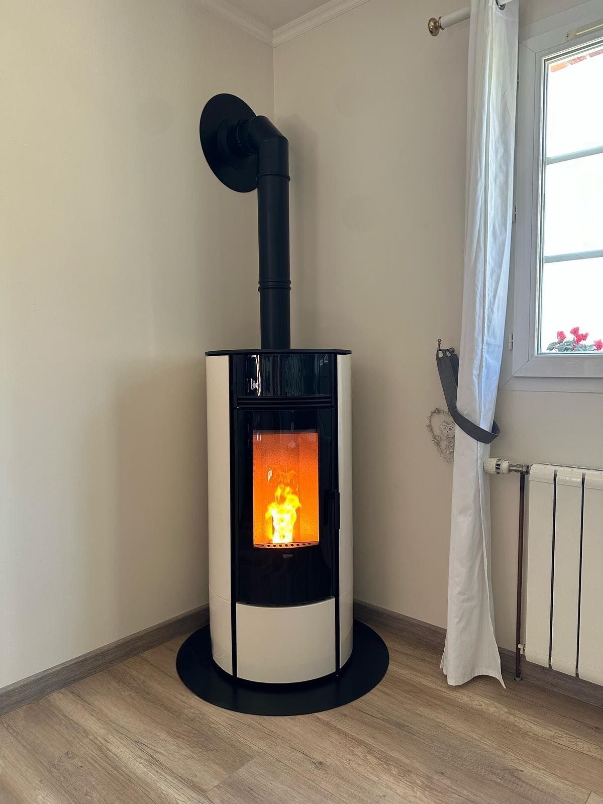Poêle à granulés noirs à flamme orange dans une pièce d'angle, près d'une fenêtre et d'un radiateur