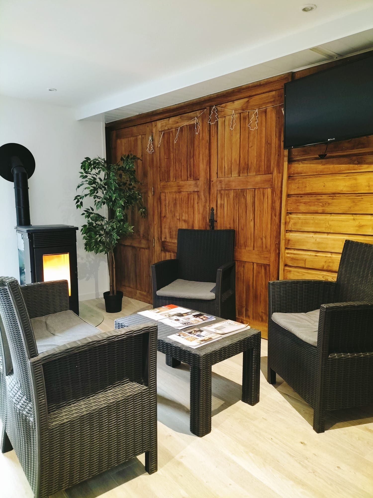 Espace d’accueil de l’agence avec coin détente et poêle à granulés en fonctionnement.