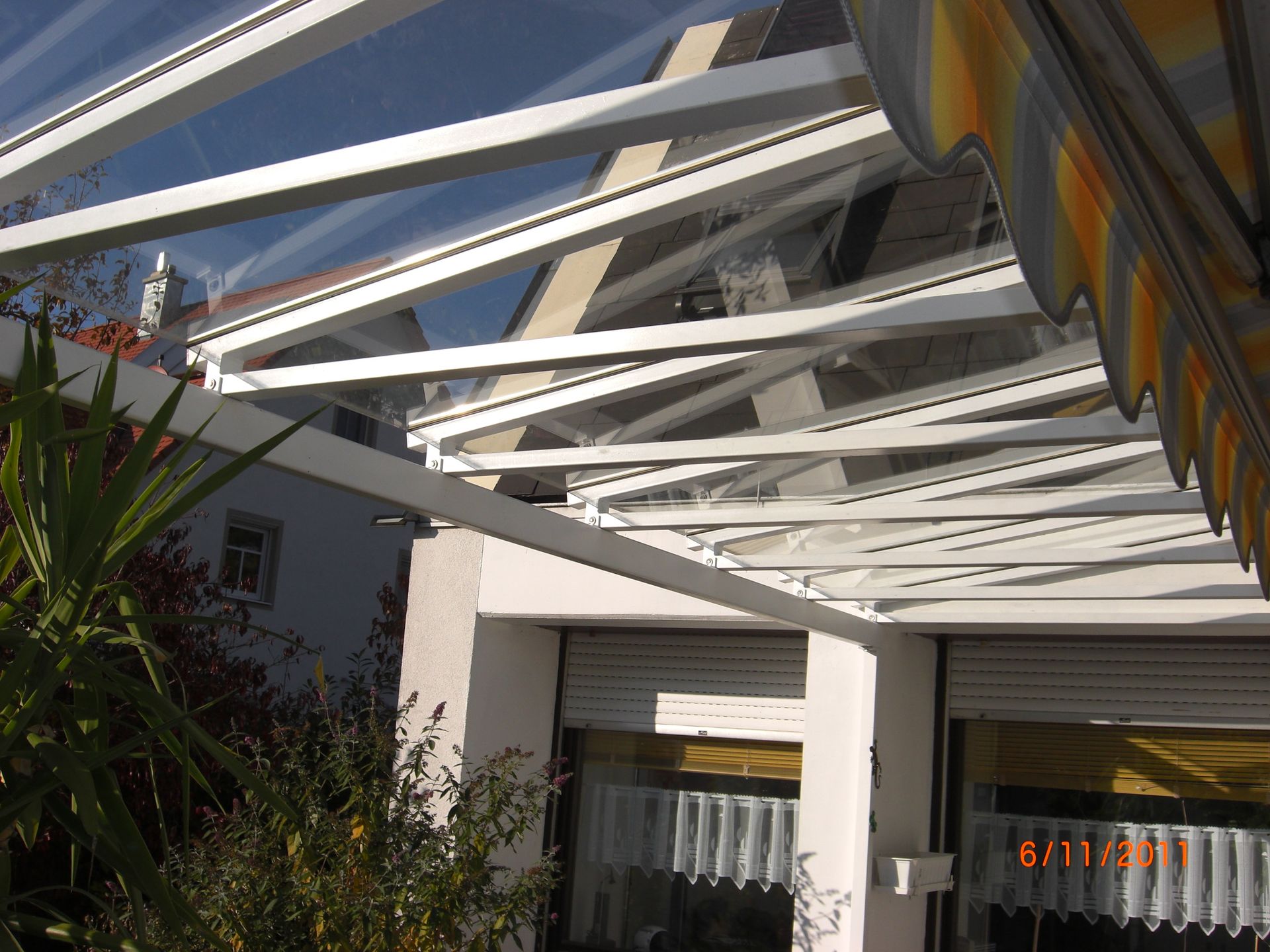 Terrassenüberdachung aus weiß lackiertem Metall und Glas