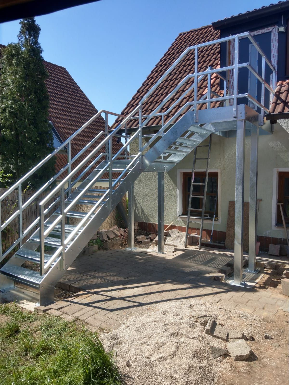 Metalltreppen mit Geländer als Verbindung einer Terrassentür in der ersten Etage zum Garten