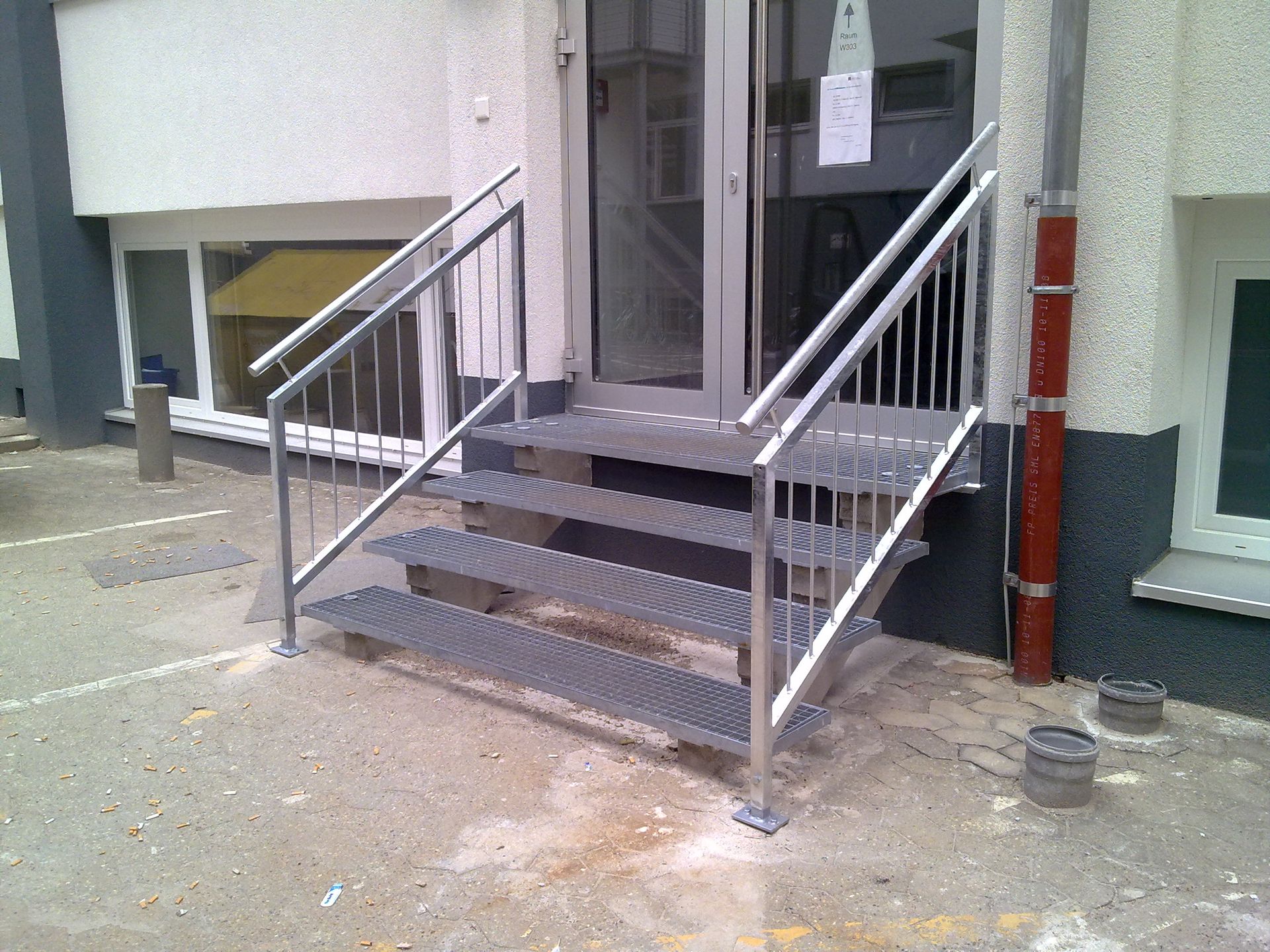 Stahltreppe mit Handlauf zu einem erhöhten Hauseingang