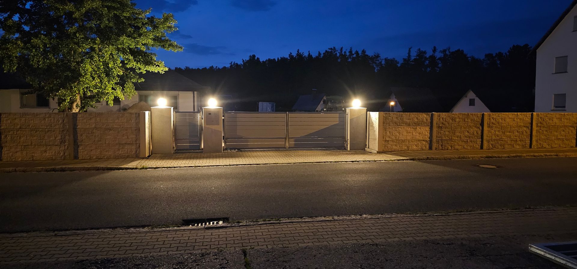 Fertigstellung des Sichtschutzes aus Naturstein und Metall mit Lichtern und automatischem Tor