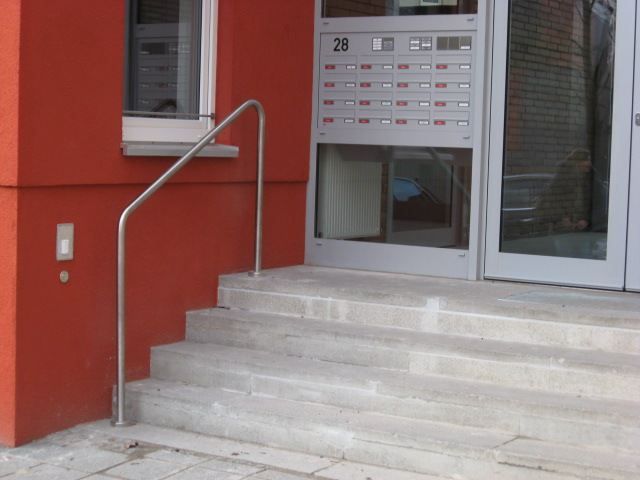 Runde Steintreppe zu einem Hauseingang mit einem Handlauf