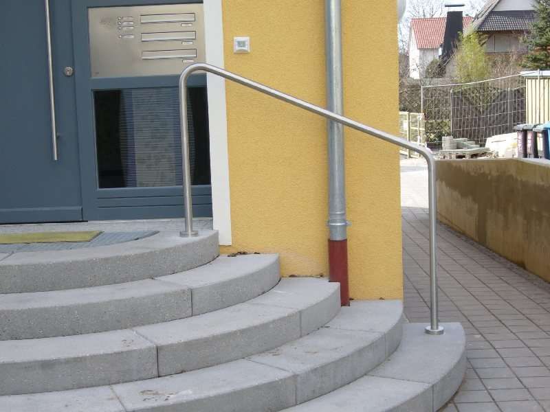 Runde Steintreppe zu einem Hauseingang mit einem Handlaufbogen